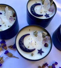 three small cups filled with different types of flowers and crystals on top of a table