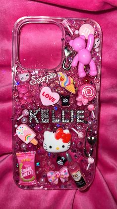 the hello kitty phone case is covered in many different items and has been placed on a pink background