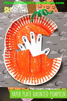 a paper plate that has been made to look like a pumpkin with ghost hands on it