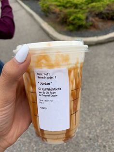 a person holding up a plastic cup with food in it's sleeve and label