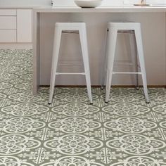 two white stools in front of a kitchen island with an ornate pattern on the floor