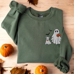 a green sweatshirt with an image of a ghost and a dog on it next to pumpkins