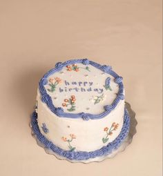 a white and blue birthday cake with flowers on it