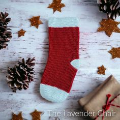 a red and white crocheted stocking next to christmas decorations