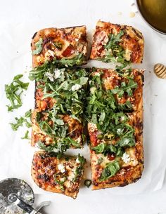 several slices of pizza on top of a white plate next to a bowl and utensils