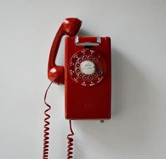 an old fashioned red telephone on a white wall