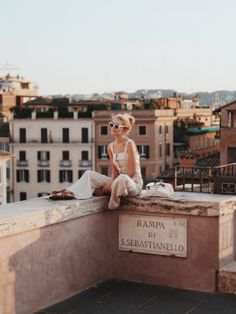 a woman sitting on top of a building next to a sign that says rama di sebastianello