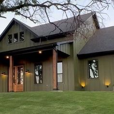 a large house sitting on top of a lush green field next to a tree in front of it