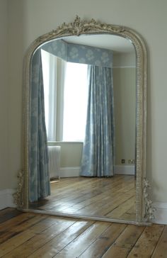 a large mirror sitting on top of a wooden floor