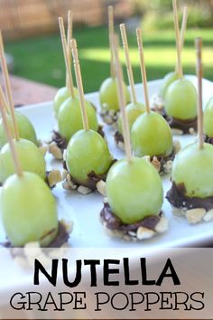 chocolate covered apples are arranged on a white platter with toothpicks in them