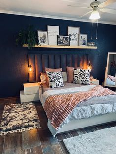 a bedroom with blue walls and wooden floors has a bed, rugs, lamps, and pictures on the wall