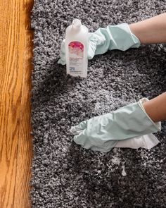 someone wearing gloves and rubber gloves is cleaning the carpet with a bottle of disinfectant