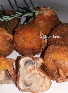 some fried food on a white plate with a sprig of rosemary next to it