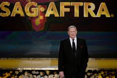 a man in a black suit and tie standing at a podium with the words sag affra on it