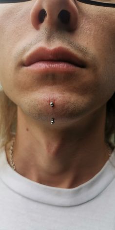 a close up of a man with glasses on his face and nose piercings attached to his nose