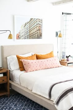 a bedroom with a bed, nightstands and pictures on the wall above it in orange