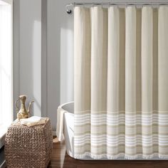 a bath tub sitting next to a window with curtains on the shower curtain and rug