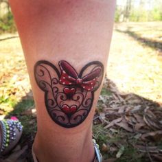 a woman's leg with a tattoo on it that has a mouse in the shape of a heart