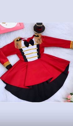 a red and black uniform is laying on a white furnishing next to flowers