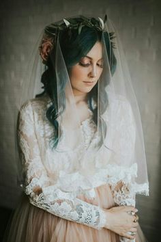 a woman with blue hair wearing a veil and holding her hands in her pockets while looking down