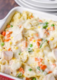 a casserole dish with chicken, peas and carrots in it on a table