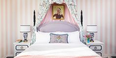 a bedroom with pink and white striped walls, a bed covered in pillows and a painting on the wall