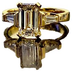 Dekara Design Collection Metal-18K Yellow Gold, 18K White Gold, .750. Stones- Center GIA Certified Emerald Cut Diamond J Color VS1 Clarity 1.62 Carats, Two Sides Baguette Diamonds H-I Color VS1-VS2 Clarity 0.40 Carats. GIA Report # 1353255620 Size- 6 3/4. FREE SIZING!!!! 18K Yellow Gold Emerald Cut Diamond Engagement Ring Handmade By DeKara Designs. Art Deco inspired, Extremely Brilliant, Entirely Handmade, Beautiful Emerald Cut Diamond Engagement Three Stone Ring Made in 18K Yellow Gold. The ce Stone Ring Design, Emerald Cut Diamond Engagement Ring, Contemporary Engagement Rings, Emerald Cut Diamond Engagement, Asscher Cut Diamond, Handmade Engagement Rings, Modern Engagement Rings, Three Stone Engagement, Engagement Ring Cuts