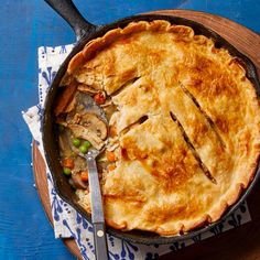 a pie sitting on top of a wooden cutting board next to a knife and fork