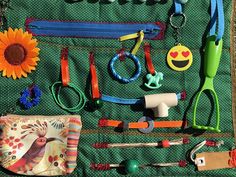 an assortment of toys and accessories laid out on a green cloth covered table with a sunflower