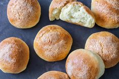 several rolls with powdered sugar on them sitting on a blue tablecloth next to a spoon