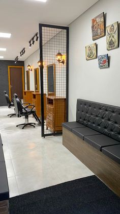 a hair salon with black leather furniture and pictures on the wall