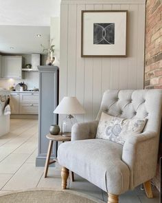 a chair sitting in front of a brick wall next to a lamp on a table