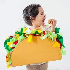 a young child wearing a taco costume and holding a doughnut