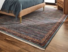 a bed sitting on top of a wooden floor next to a blue and red rug