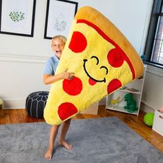 a young boy holding up a giant pizza pillow