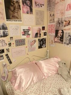 a bed with pink sheets and pictures on the wall next to a teddy bear sitting on top of it