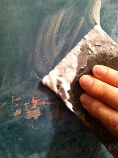 a hand holding a sponge on top of a piece of paper