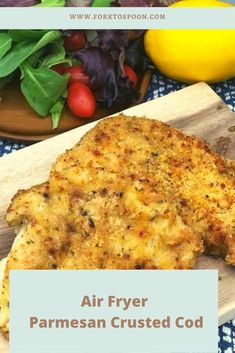 an air fryer parmesan crusted chicken on a cutting board next to vegetables