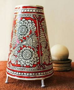 a red and white vase sitting on top of a wooden table next to an egg