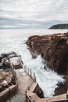 the steps lead down to the beach where waves crash against the rocks and into the water