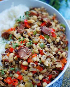 a white bowl filled with rice, beans and sausage on top of it's side