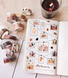 an open notebook sitting on top of a wooden table next to washi tapes and a candle