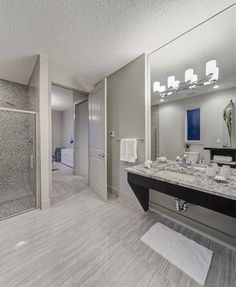 a bathroom with marble counter tops and large mirrors on the wall, along with a walk in shower