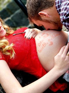 a pregnant woman with writing on her stomach is being examined by a man in a red shirt