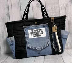 a black and blue bag with a quote on it's side, hanging from a wooden wall