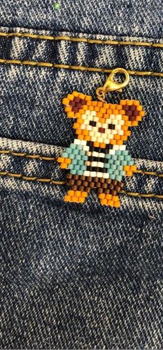 a teddy bear keychain hanging from the back pocket of a pair of jeans