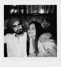 black and white photo of two people sitting next to each other, one man has his arm around the woman's shoulder