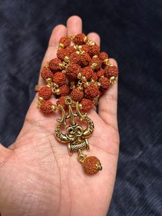 This bold and beautiful Shiva Trident pendant comes on an rudraksh mala gold cap. This is a beautiful way to celebrate your divine masculine energy whatever your gender, and is a beautiful gift for adorning your masculine beloved. See below for more information about this potent, tantric symbol and its meaning. A great gift for yogis and those studying tantra. Brass will oxidize to a more antiqued color over time. If you would like it to be bright and shiny again, just use a little bit of lemon Spiritual Locket Necklace For Navratri, Spiritual Necklaces For Navratri Gift, Spiritual Necklaces For Navratri, Spiritual Gold Temple Necklace For Meditation, Gold Necklaces With 108 Beads For Rituals, Spiritual Temple Necklace For Festival Gifts, Gold Mala As Navratri Gift, Spiritual Locket Necklace For Diwali, Gold Mala For Navratri Gift