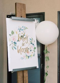 a white balloon is in front of a sign that says baby's n bloom