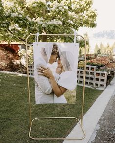 a wedding photo hanging on a clothes line in front of a garden with trees and flowers